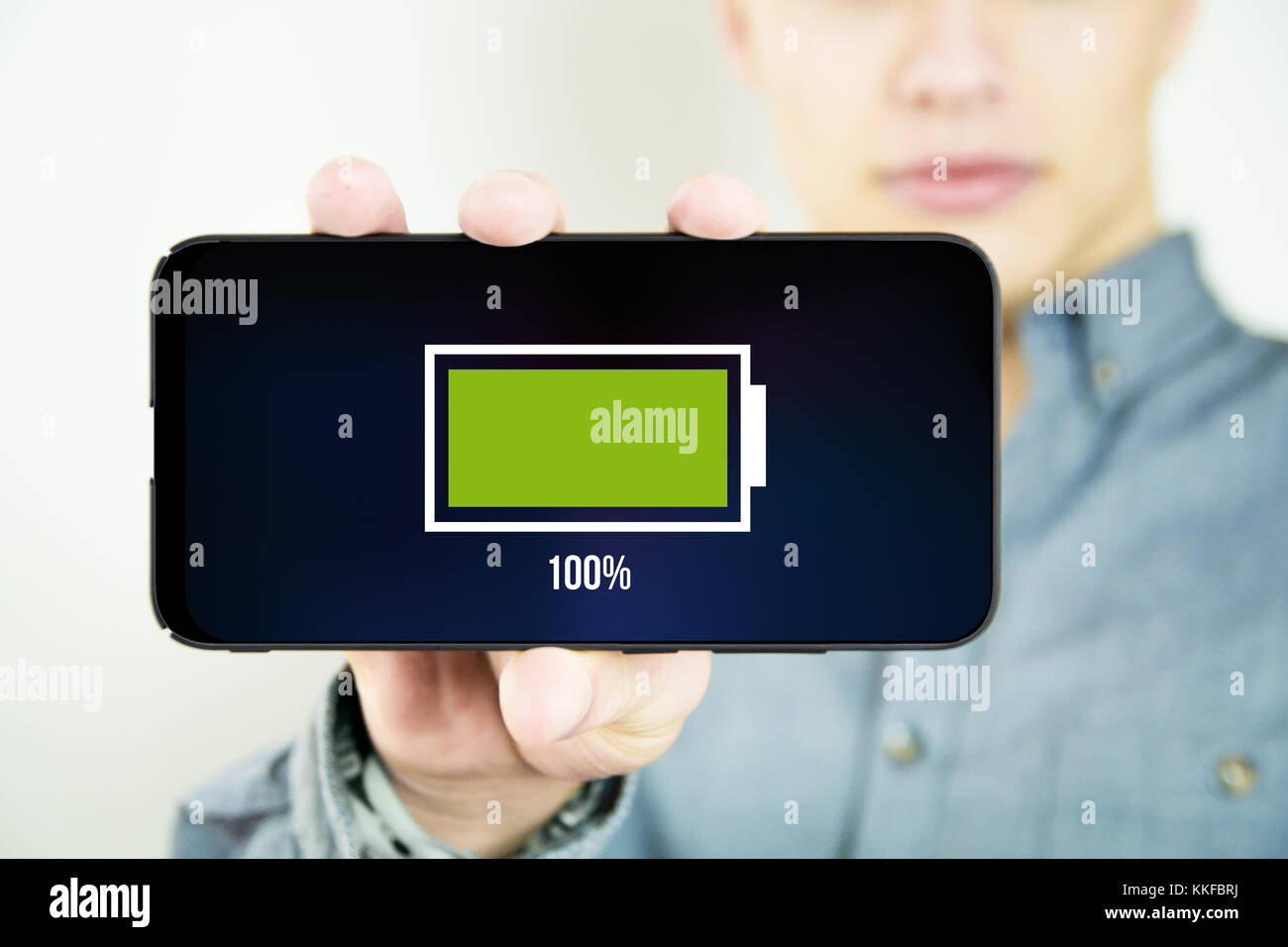 young man holding and showing a full battery full screen smartphone Stock Photo