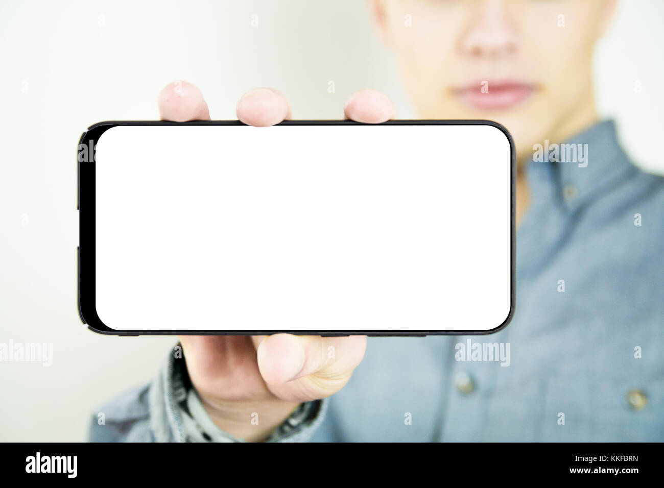 young man holding and showing a blank full screen smartphone Stock Photo