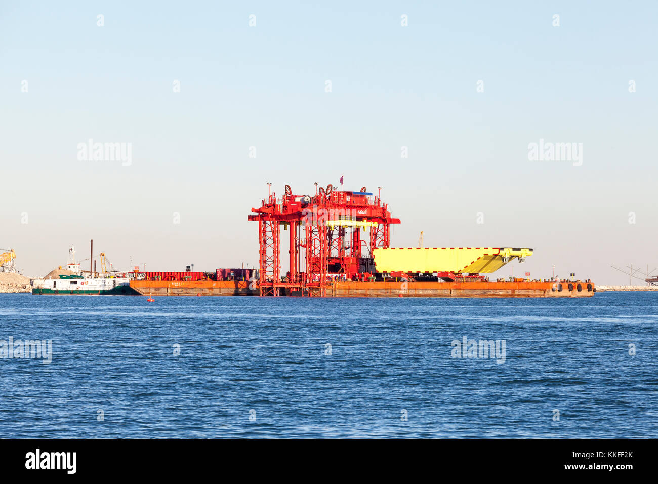The MOSE project barrier and gantry lift at the Chioggia lagoon entrance, Venice, Italy with one 210 ton gate raised on a barge  being inspected by en Stock Photo