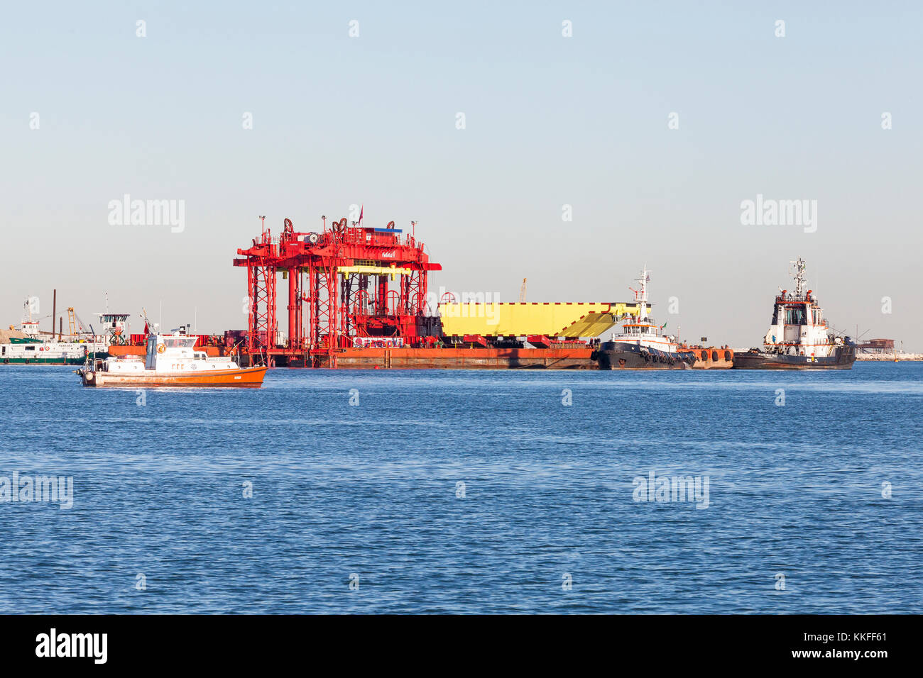 The MOSE project barrier and gantry lift at the Chioggia lagoon entrance, Venice, Italy with one 210 ton gate raised on a barge  with tugs in attenda Stock Photo