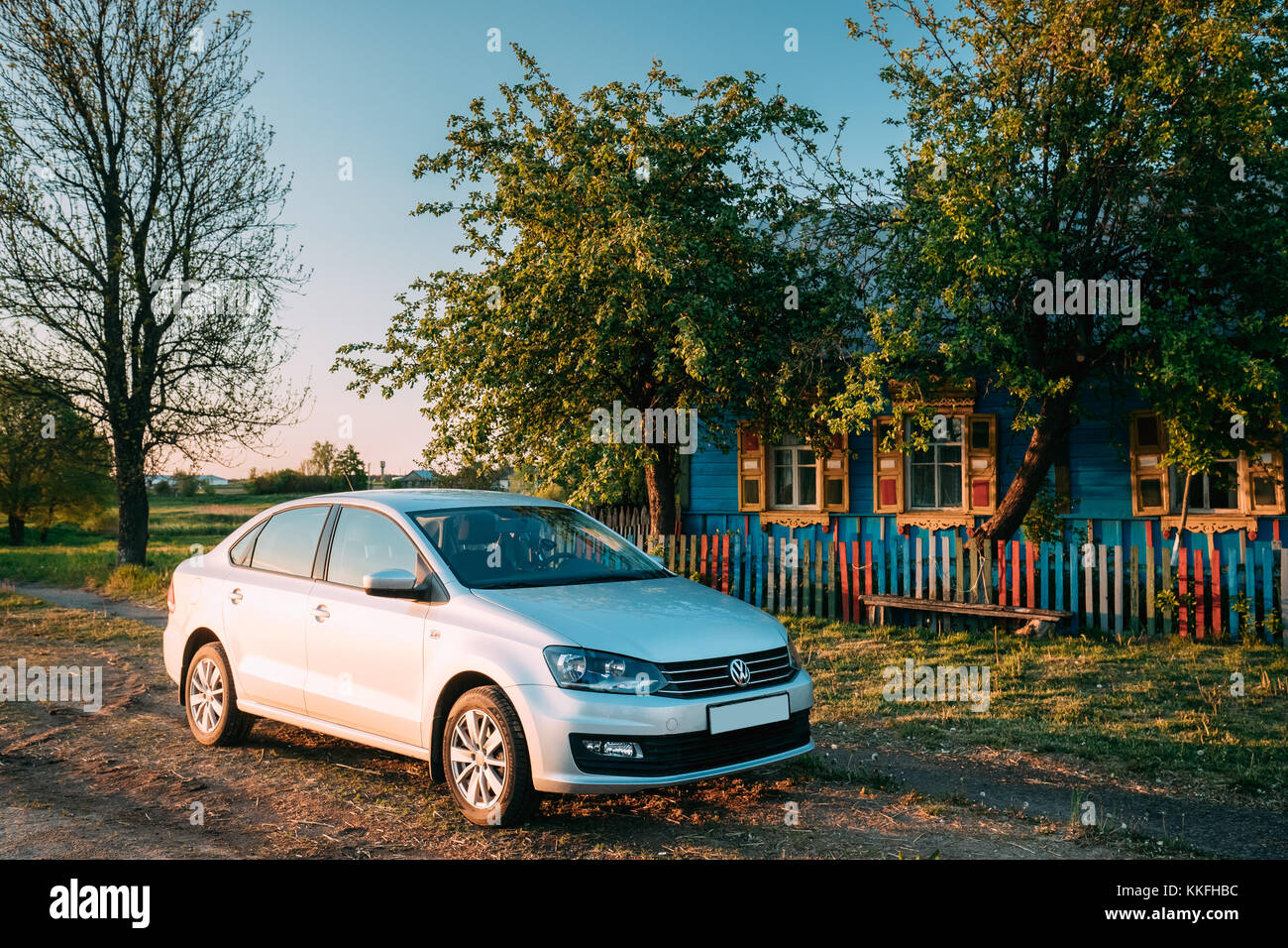 Krasnyy Partizan - May 16, 2017: VW Volkswagen Polo Vento Sedan Car Parking Near Traditional Russian Wooden Old House In Village. Sunny Evening In Cou Stock Photo