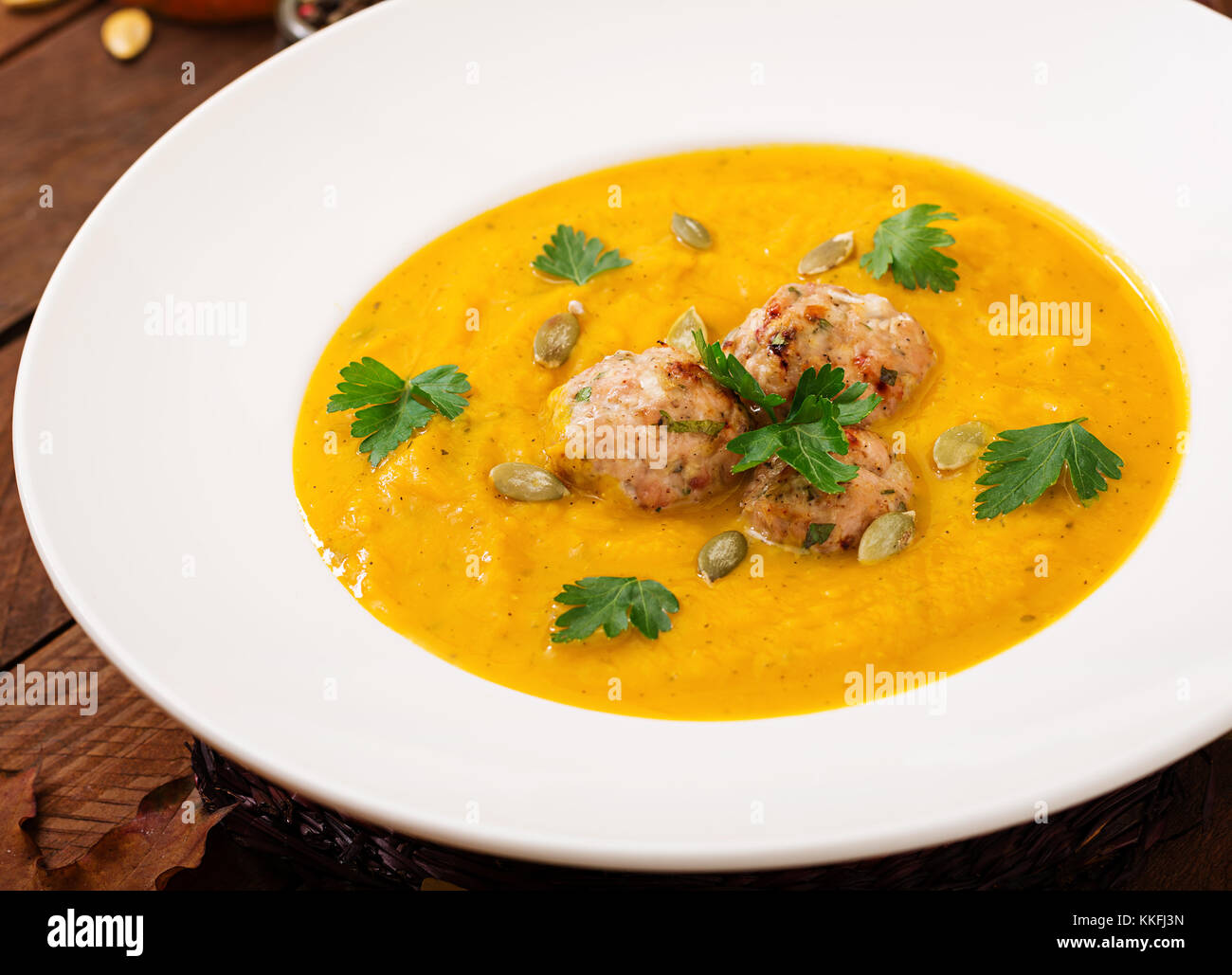 Delicious cream of pumpkin soup with meatballs made of turkey minced meat in a bowl on a wooden table. View from above. Thanksgiving Day. Stock Photo