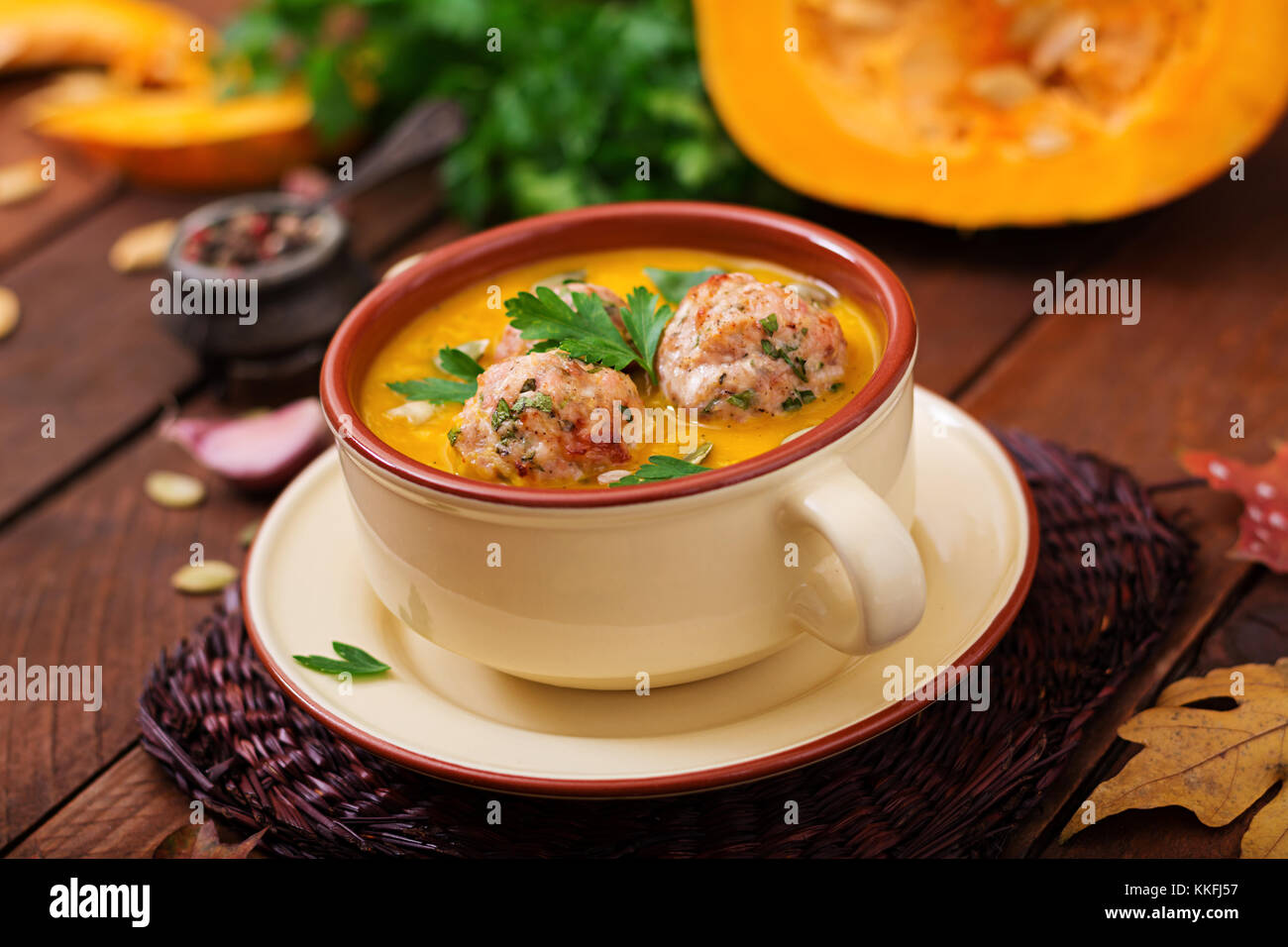 Delicious cream of pumpkin soup with meatballs made of turkey minced meat in a bowl on a wooden table. View from above. Thanksgiving Day. Stock Photo