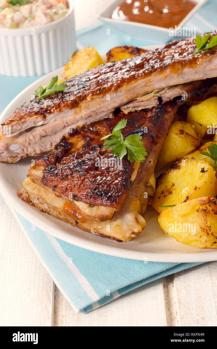 Fresh baked golden potatoes and beef ribs in bbq sauce on wooden