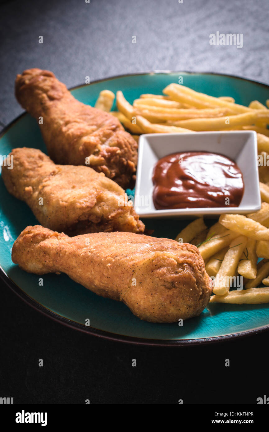 Fried chicken legs and French fries with bbq sauce in the plate