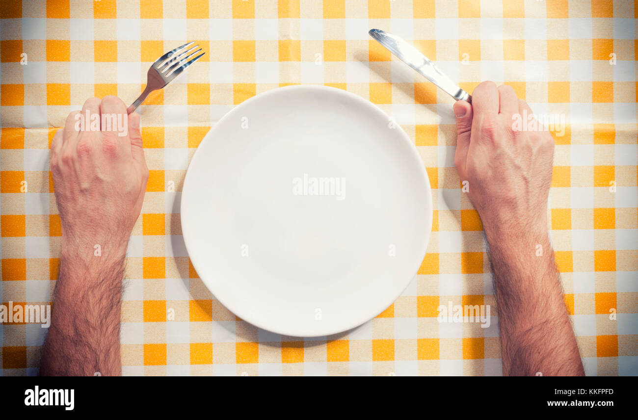 Male hand holding knife and fork near the empty plate Stock Photo Alamy