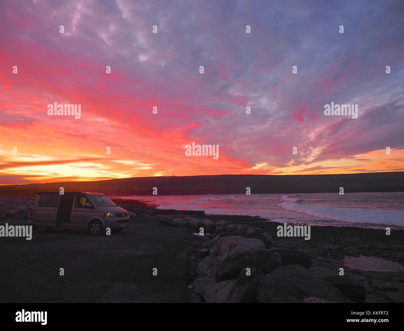 The sun rises over the Wild Atlantic Way at Doolin Pier, County Clare, Ireland turning the rock pools a sunburst red. Stock Photo