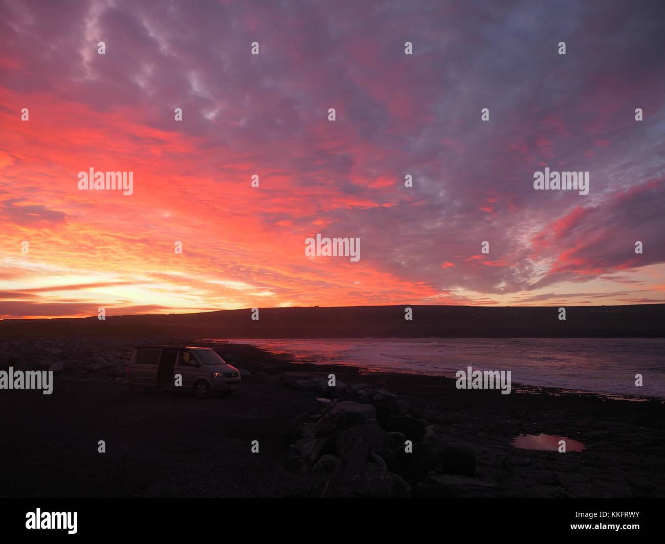 The sun rises over the Wild Atlantic Way at Doolin Pier, County Clare, Ireland turning the rock pools a sunburst red. Stock Photo