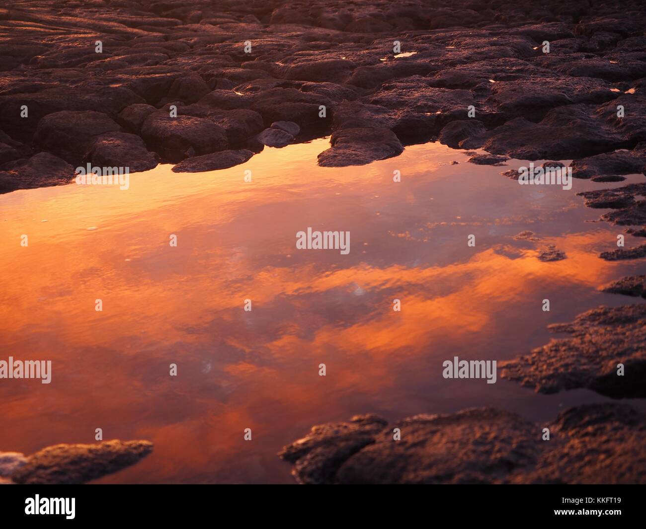 The sun rises over the Wild Atlantic Way at Doolin Pier, County Clare, Ireland turning the rock pools a sunburst red. Stock Photo