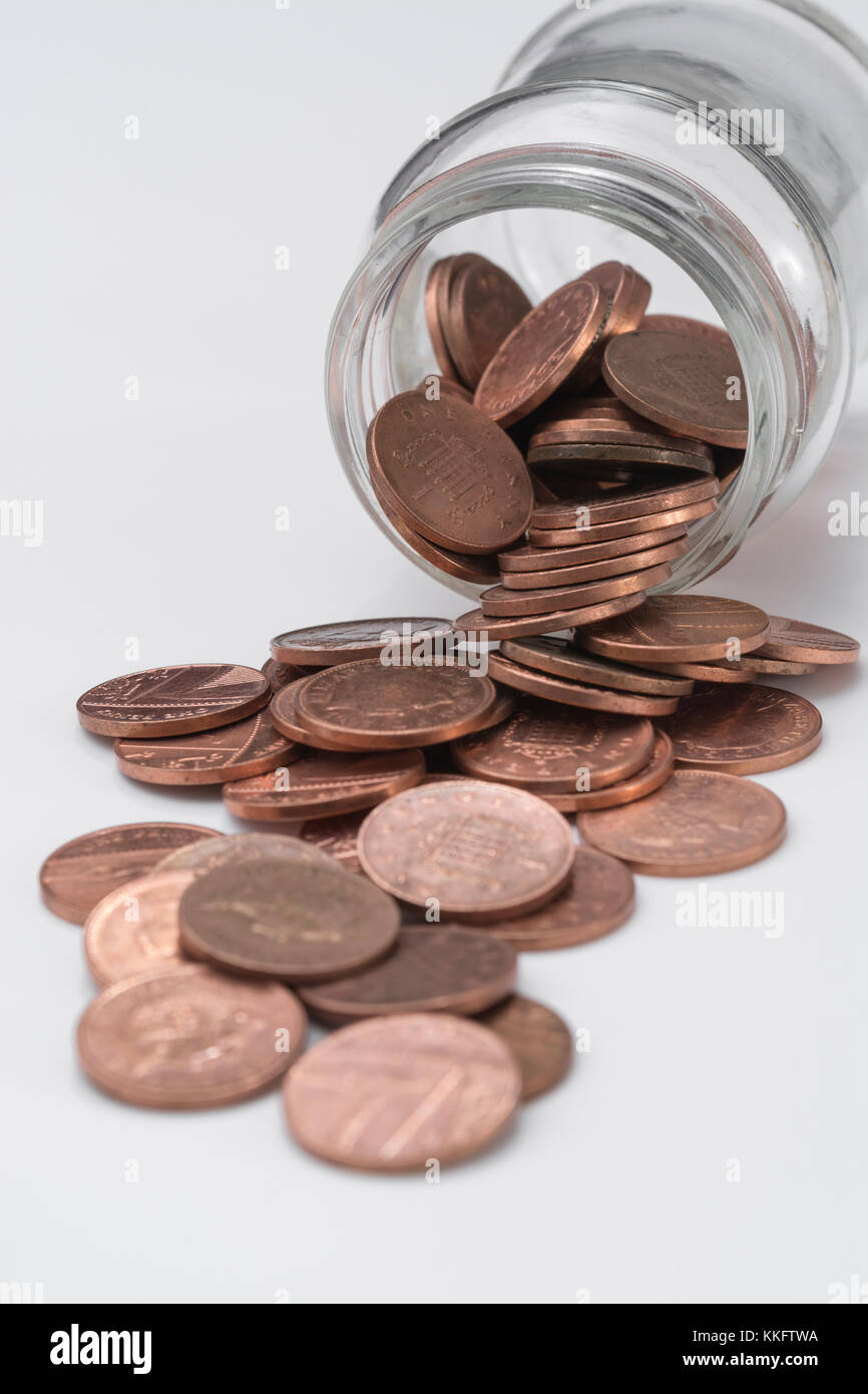 UK copper pennies cascading from glass jar. Saving pennies money, kitchen table issues, look after the pennies, pennywise, saving, 1p penny challenge Stock Photo