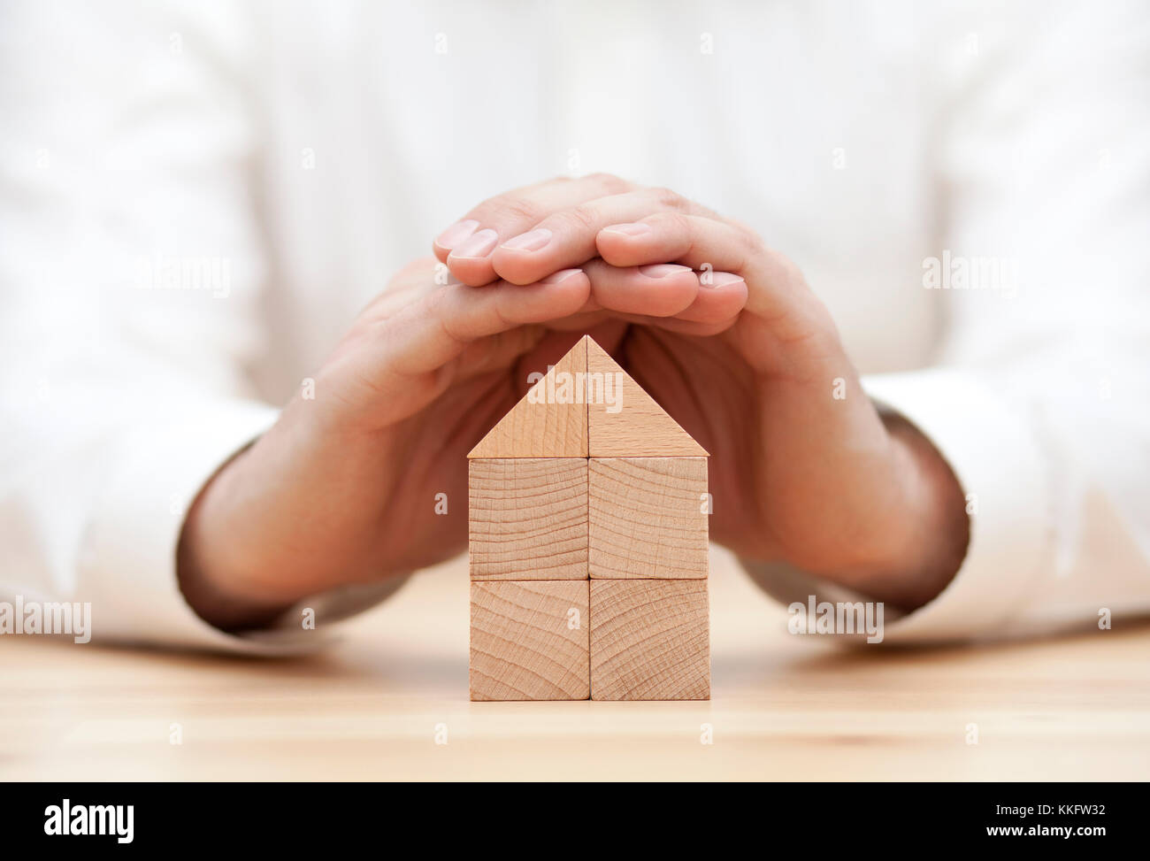 Wooden block house protected by hands Stock Photo