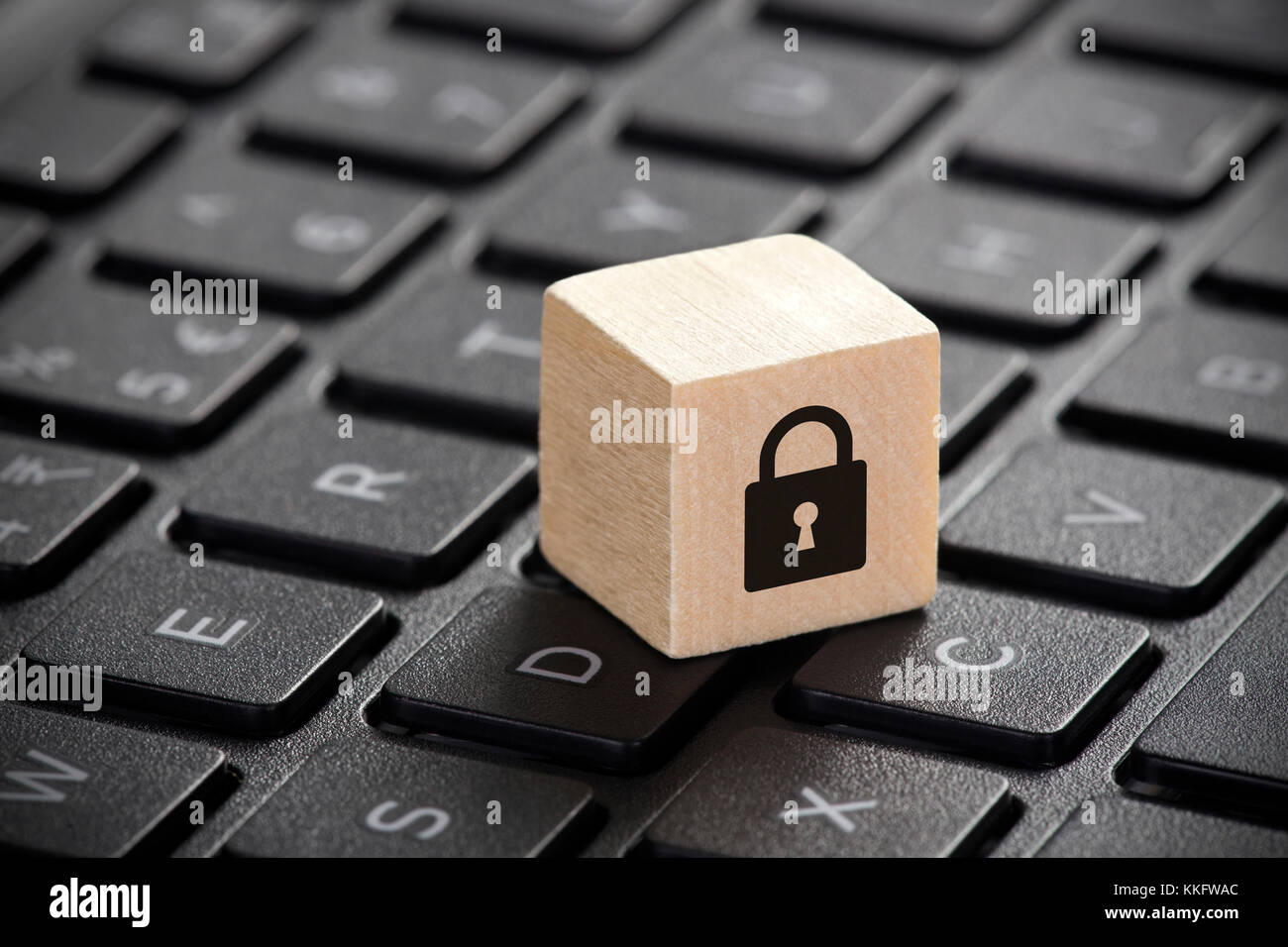 Wooden block with lock graphic on laptop keyboard. Computer security concept. Stock Photo
