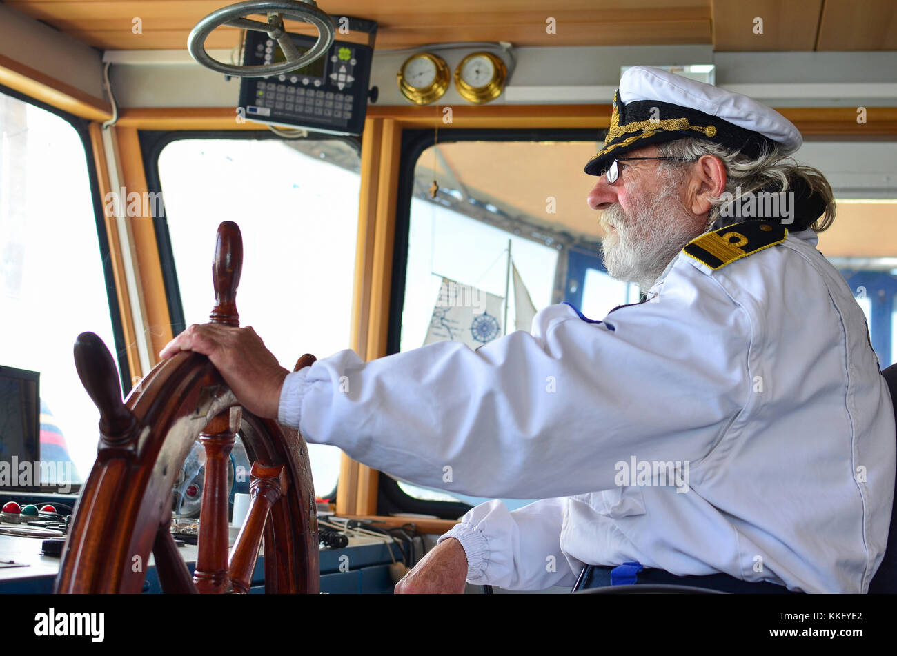 Ship navigation, experienced captain, old sea dog with grey hair and beard on his working place, ship navigation cabine Stock Photo