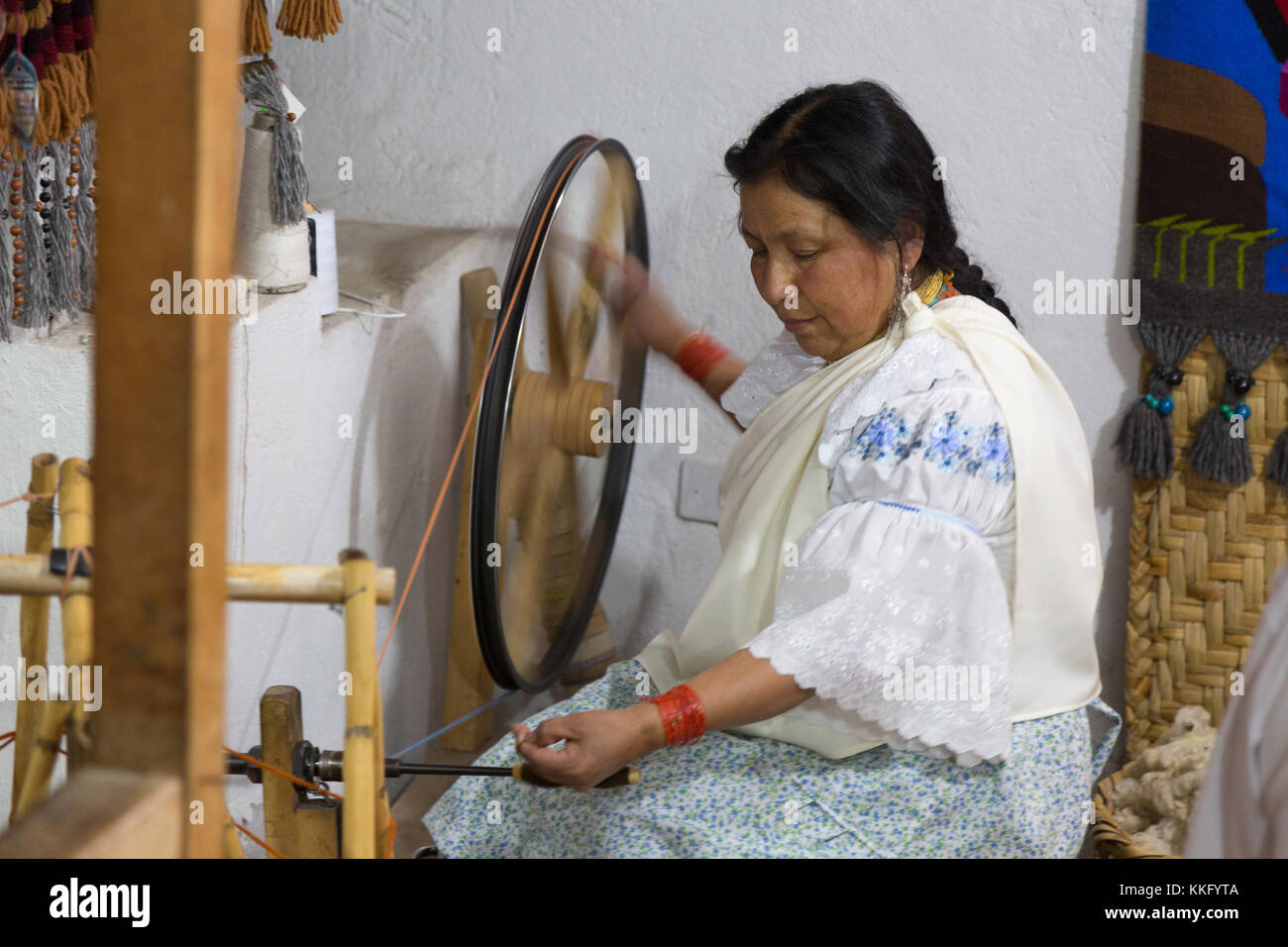 Ecuador Culture - an ecuadorian mature woman using a traditional spinning wheel spinning yarn to make textiles, Otavalo, Ecuador, South America Stock Photo