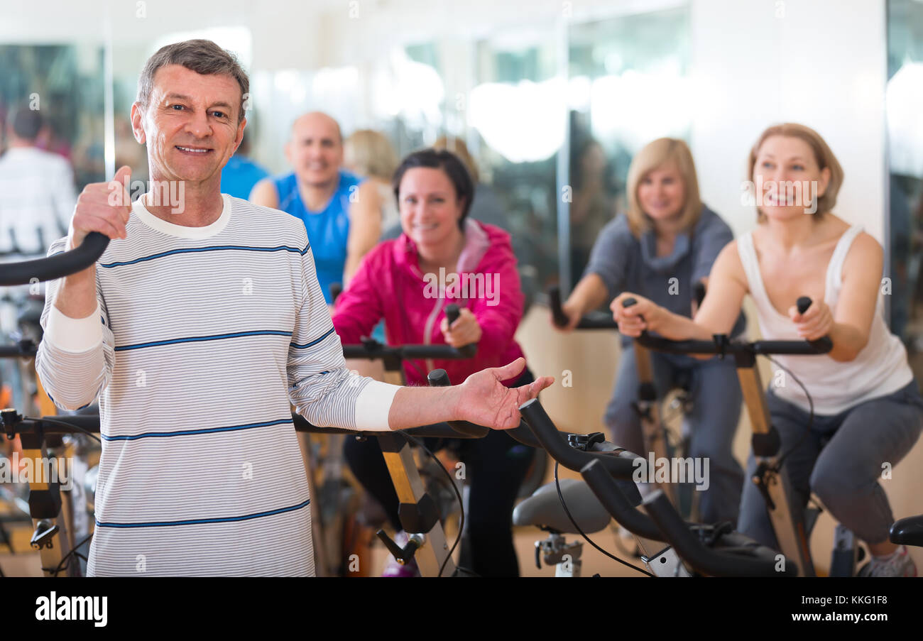 Smiling elderly man on fitness cycle in fitness club Stock Photo