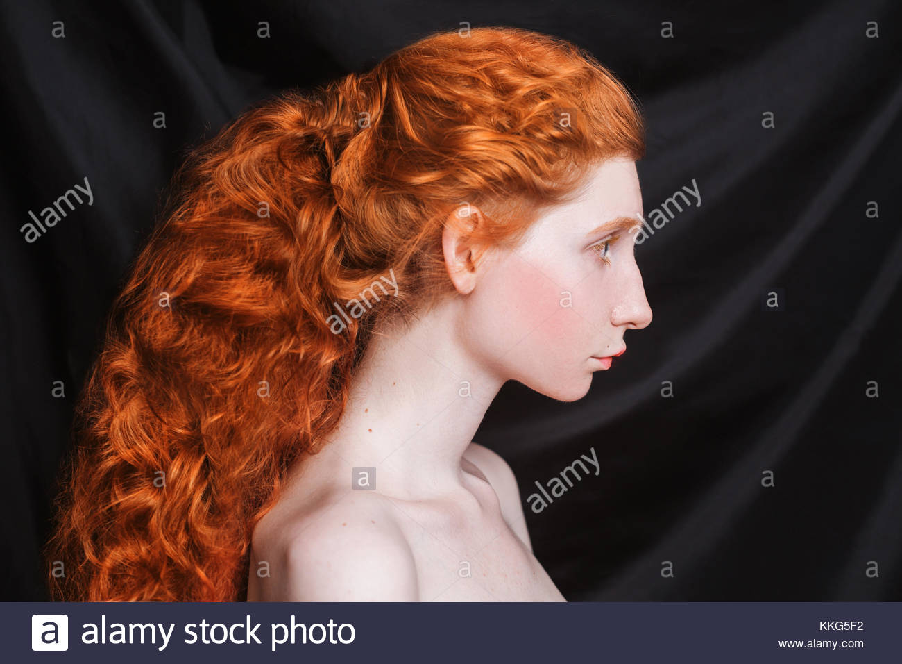 Woman With Long Curly Red Hair Gathered In Ponytail On Black Stock