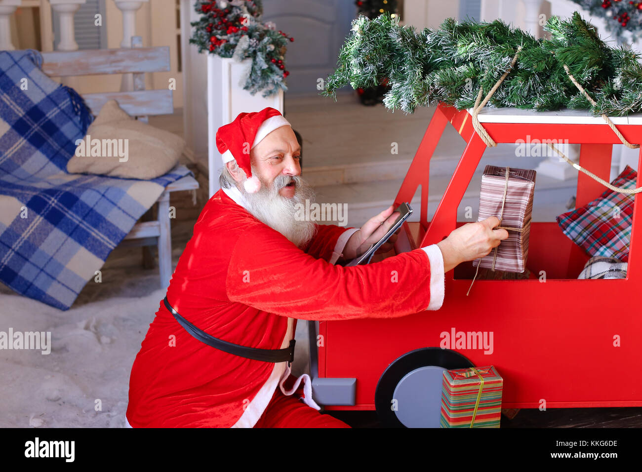Santa Claus checking list of presents on tablet and putting gift Stock ...