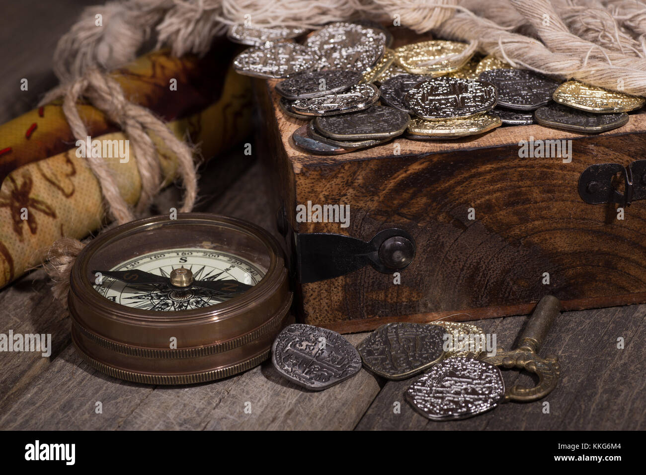 Closeup of gold and silver coins in a treaure chest with compass and