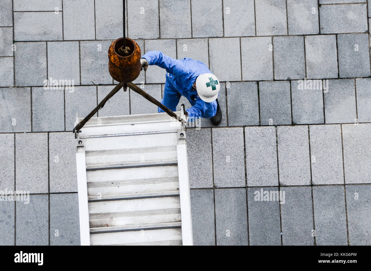 Dock worker positions lowering of ramp from crane for cruise ship. Looking down on worker position equipment using crane. Teamwork concept. Stock Photo