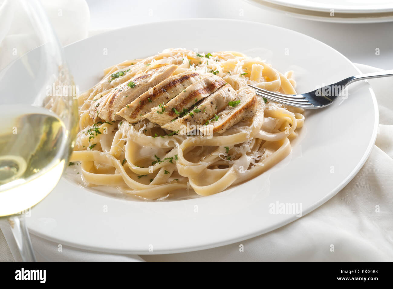 Delicious grilled chicken alfredo with fettuccine, grated parmigiano reggiano, and chopped parsley garnish. Stock Photo