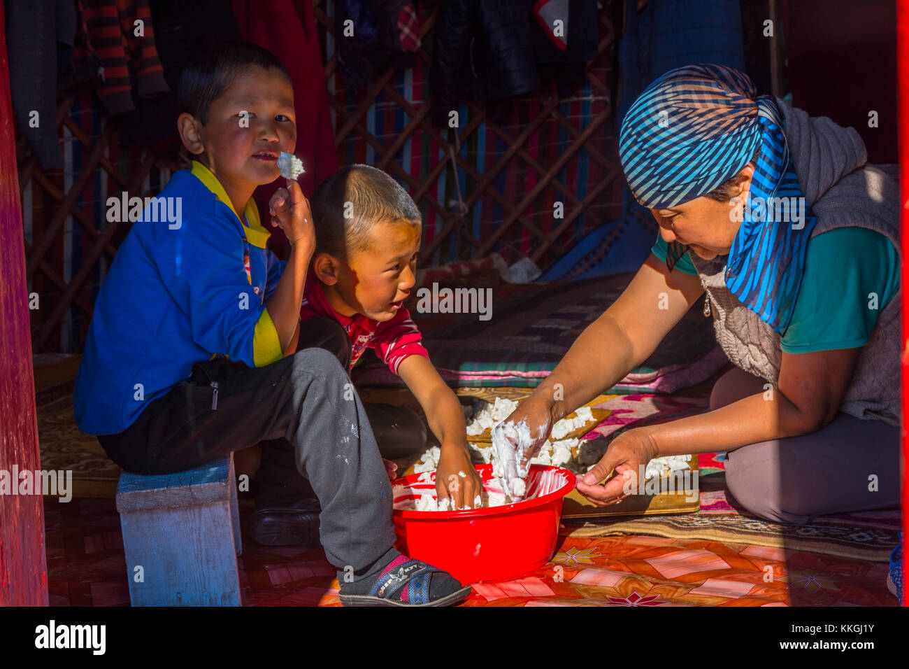 SONG KUL, KYRGYZSTAN - AUGUST 11: Woman and two kids making kurut, traditional cheese balls in a yurt. August 2016 Stock Photo