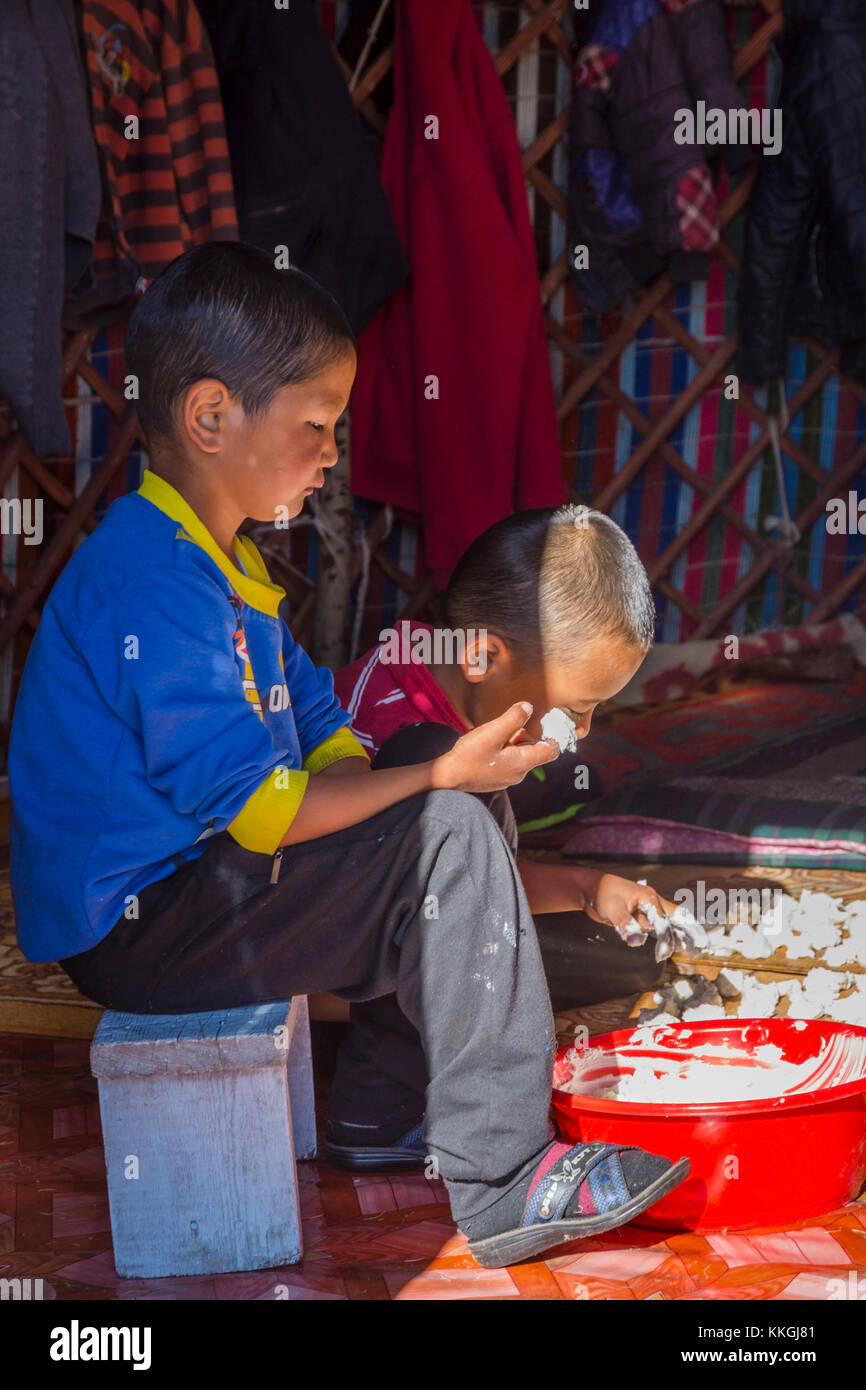 SONG KUL, KYRGYZSTAN - AUGUST 11: Two kids making and tasting kurut, traditional cheese balls in a yurt. August 2016 Stock Photo