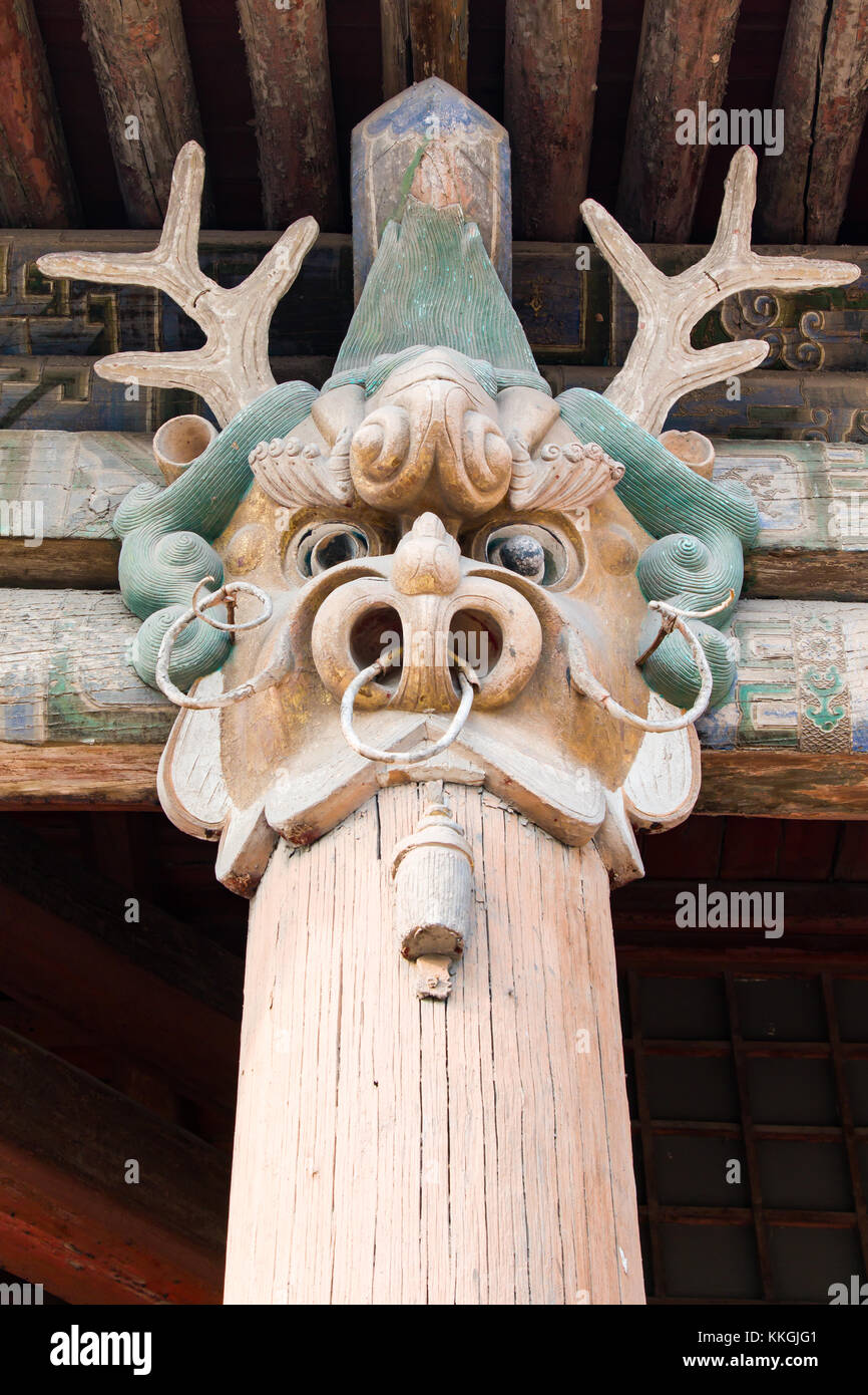 A dragon head carved into the top of a wooden support pillar Stock