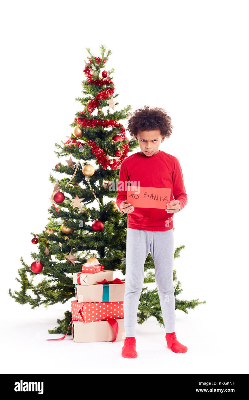 Mixed race boy near Christmas tree Stock Photo