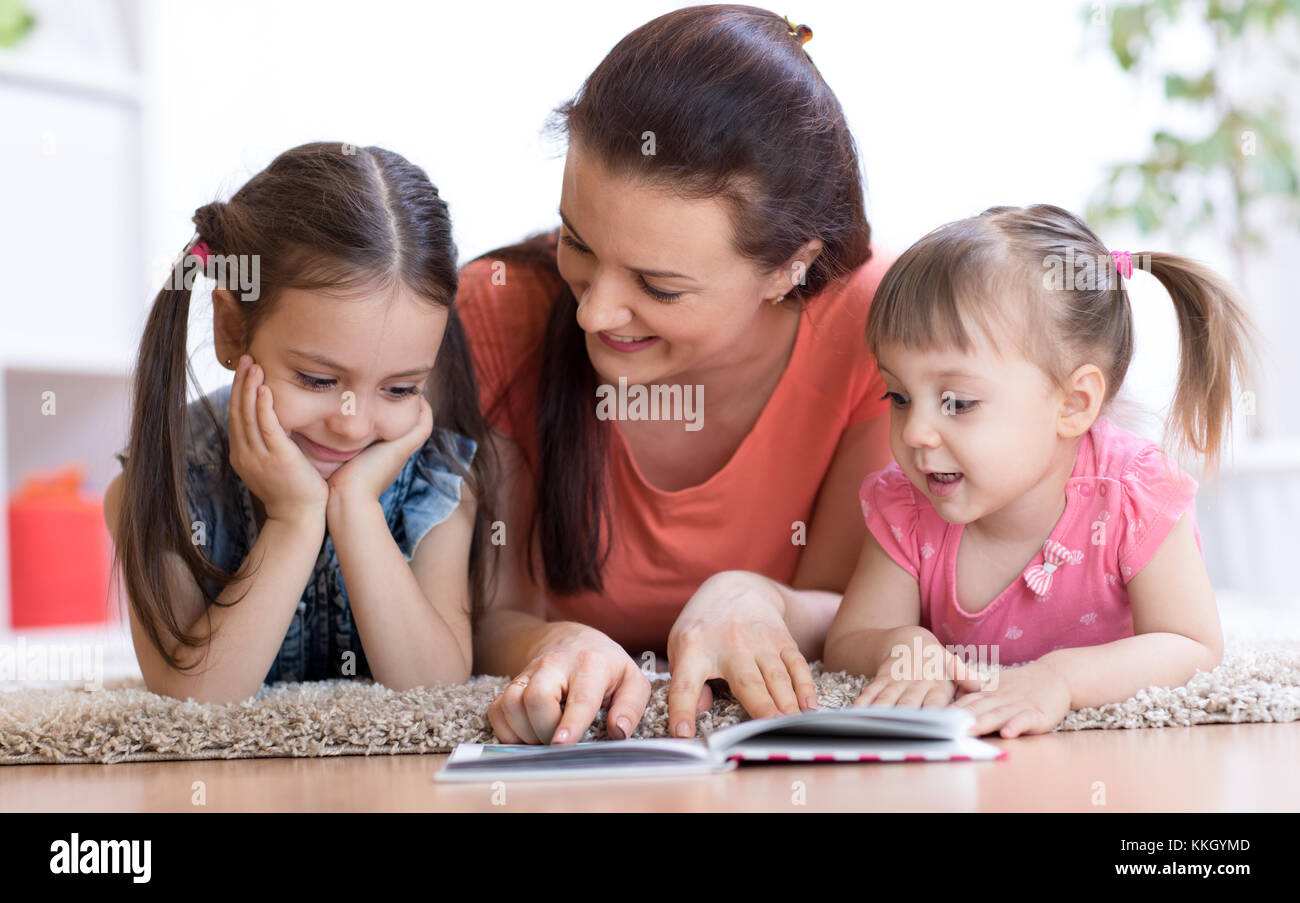 Pretty mother reading a book to her daughters. Stock Photo