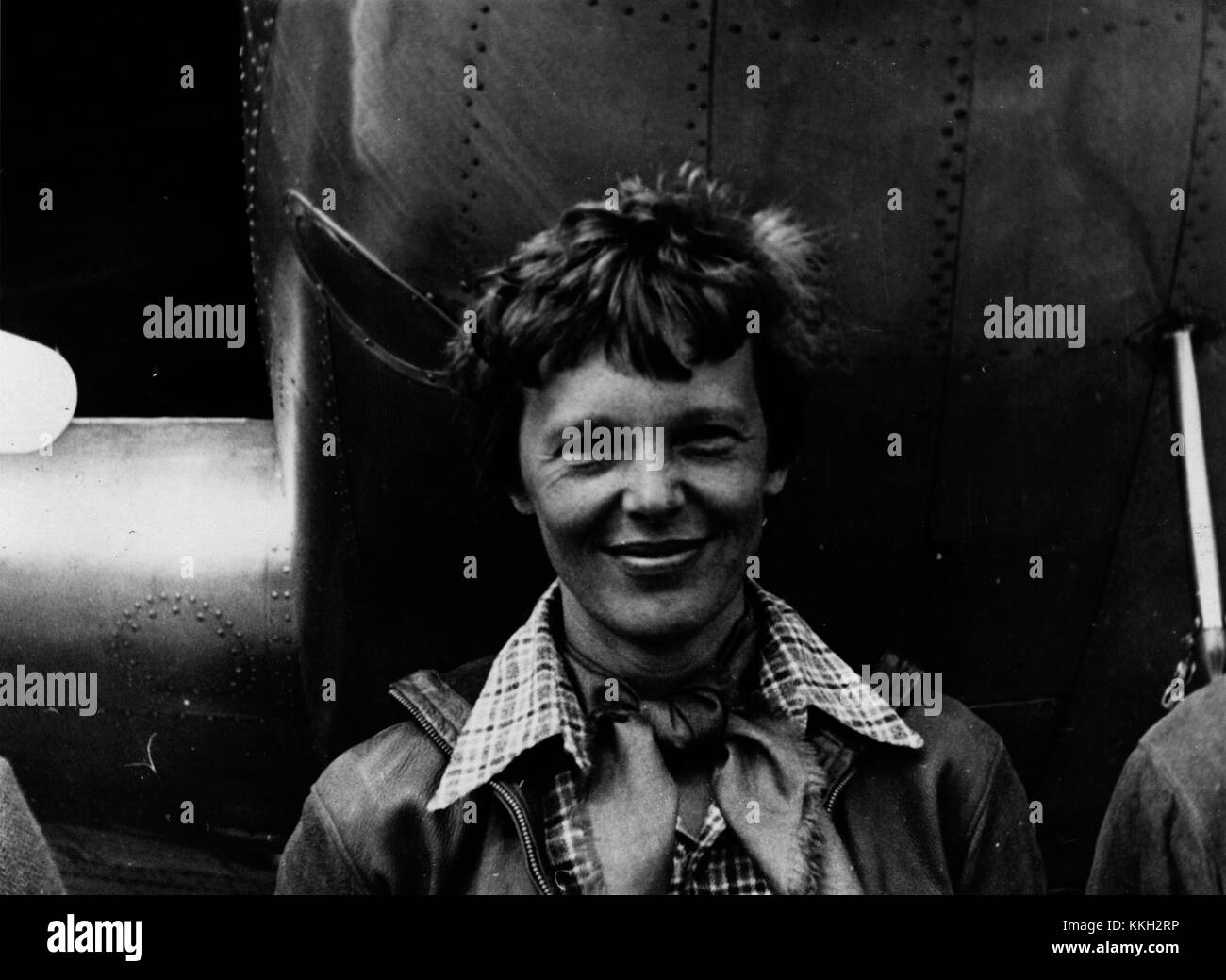 Informal head and shoulders portrait of Amelia Earhart standing under nose of of her Lockheed Model 10-E Electra (r/n NR-16020); probably taken before her attempted flight around the world, March 1937. Amelia Earhart standing under nose of her Lockheed Model 10-E Electra Stock Photo