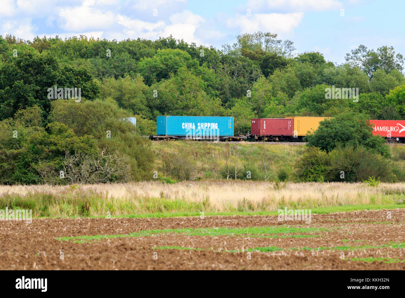 Shipping containers being transported by rail though the British countryside. Stock Photo