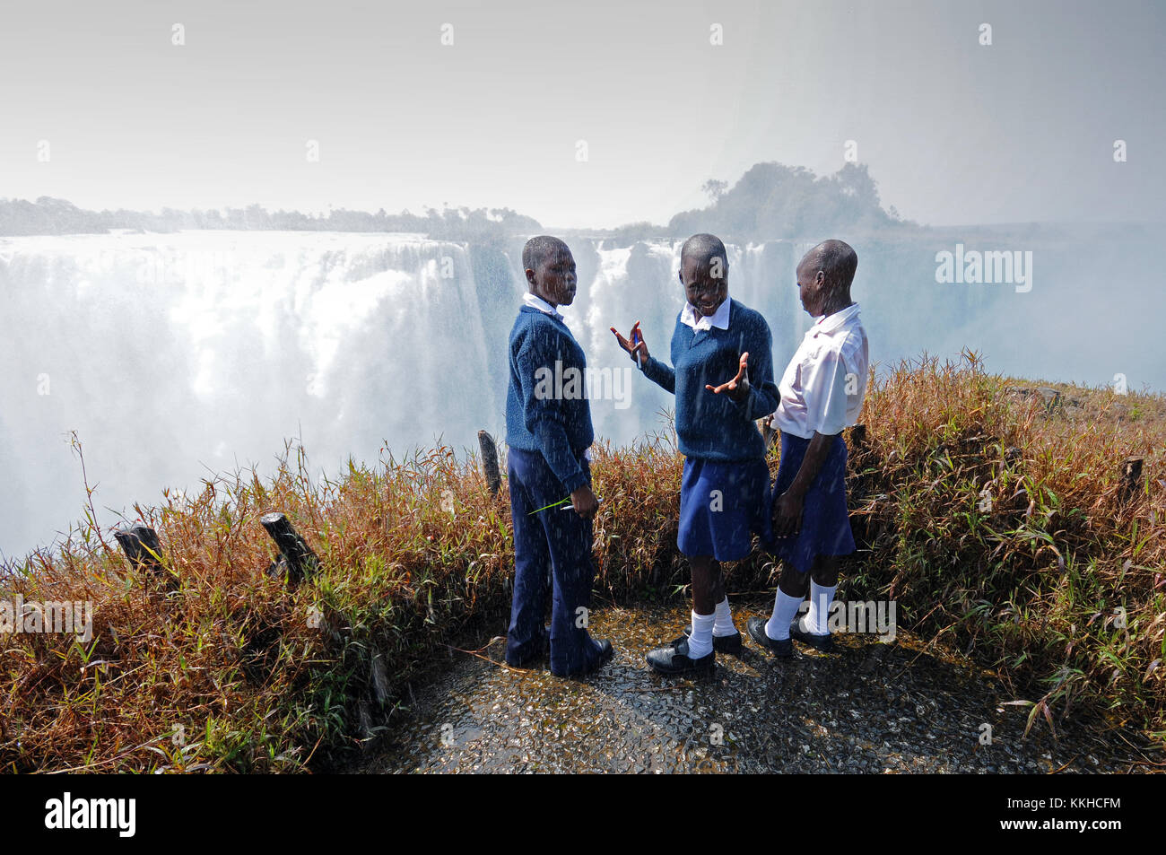 Victoria Falls, Zimbabwe. 30th July, 2015. Spray from the Victoria Falls rains down on a group of school children, pictured on 30.07.2015. The Victoria Falls are the broad waterfalls of the Zambezi at the border between Zimbabwe and Zambia. The falls were discovered by Scottish missionary David Livingstone, who named them in honour of Britain's Queen Victoria. The Victoria Falls have been a UNESCO world heritage site since 1989. The water falls up to 110 metres across a breadth of more than 1,700 metres. Credit: Matthias Tödt | usage worldwide/dpa/Alamy Live News Stock Photo