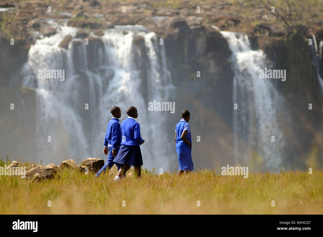 Numerous school trips from Zimbabwe visit the Victoria Falls, including these three children in school uniform, pictured on 30.07.2015. The Victoria Falls are the broad waterfalls of the Zambezi at the border between Zimbabwe and Zambia. The falls were discovered by Scottish missionary David Livingstone, who named them in honour of Britain's Queen Victoria. The Victoria Falls have been a UNESCO world heritage site since 1989. The water falls up to 110 metres across a breadth of more than 1,700 metres. Photo: Matthias Tödt | usage worldwide Stock Photo