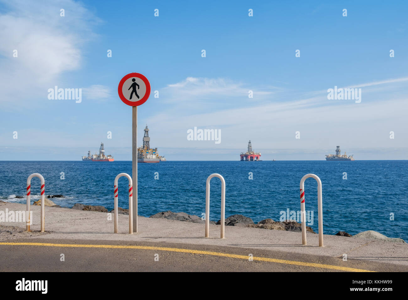 no trespass sign at end of road with ocean background, offshore drilling ships and platform on horizon Stock Photo