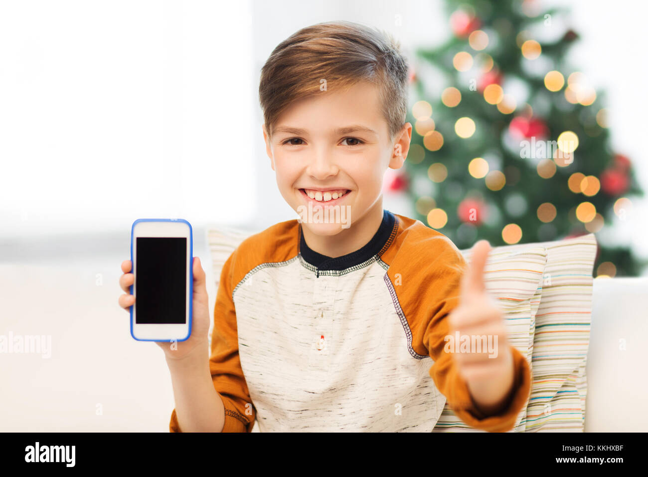 boy with smartphone at christmas showing thumbs up Stock Photo