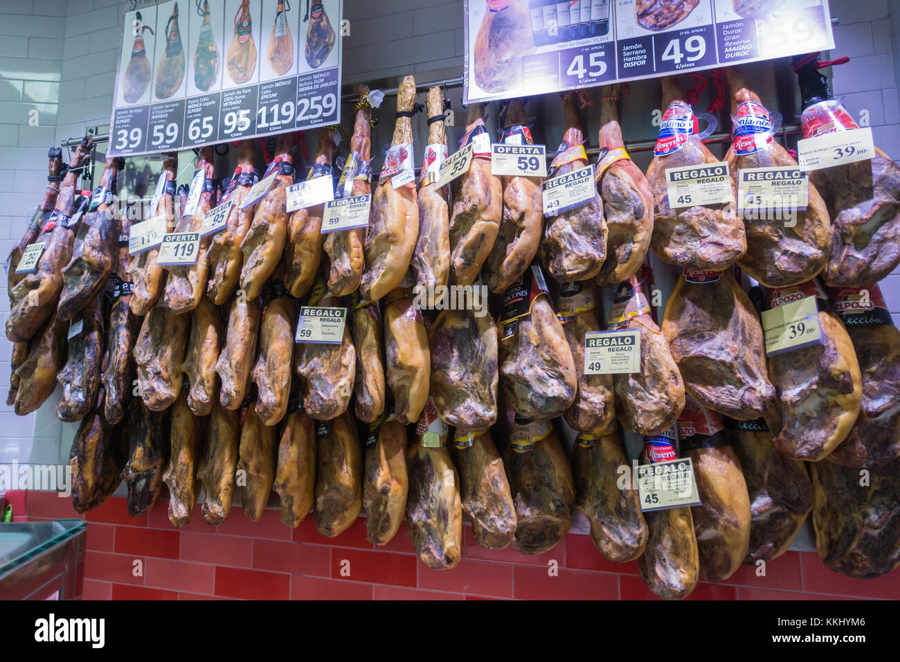 Whole legs of cured Iberian ham hanging in a Spanish supermarket with prices showing, November 2017. Stock Photo