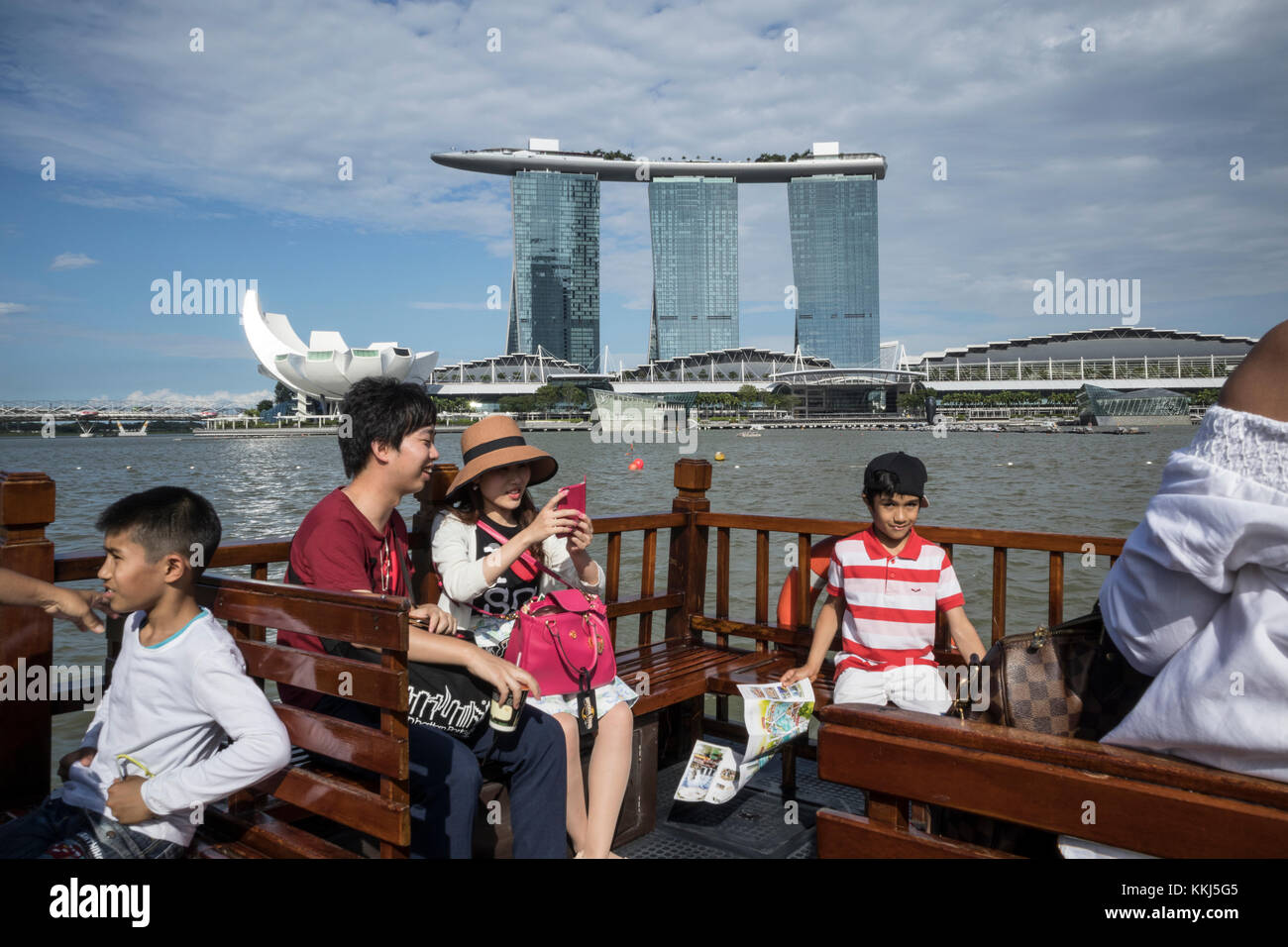 Marina Bay Sands Hotel in Singapore, with a tourist boat full of tourists in the foreground Stock Photo