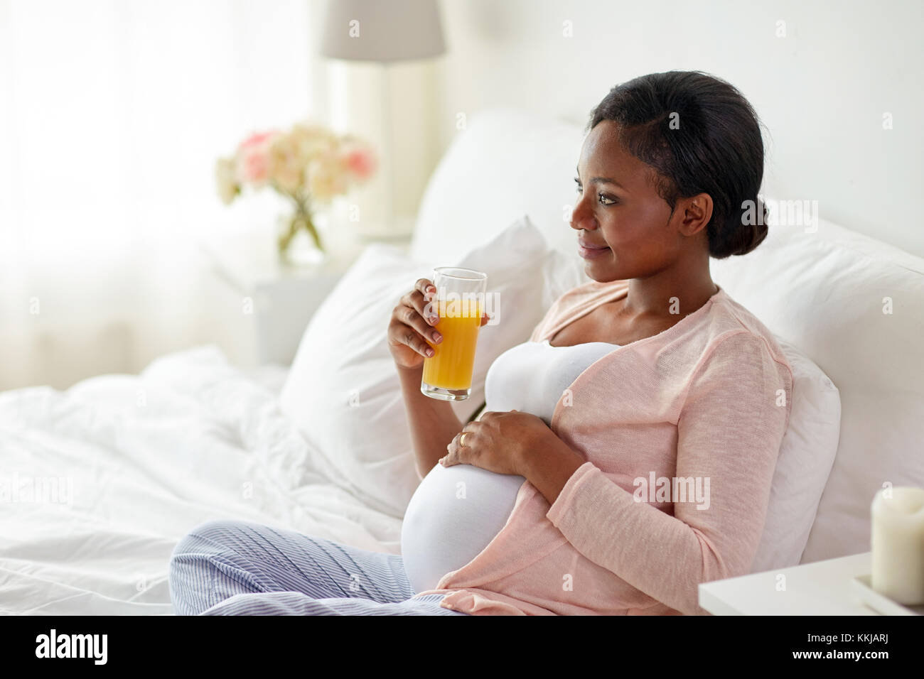 pregnant woman drinking orange juice in bed Stock Photo Alamy
