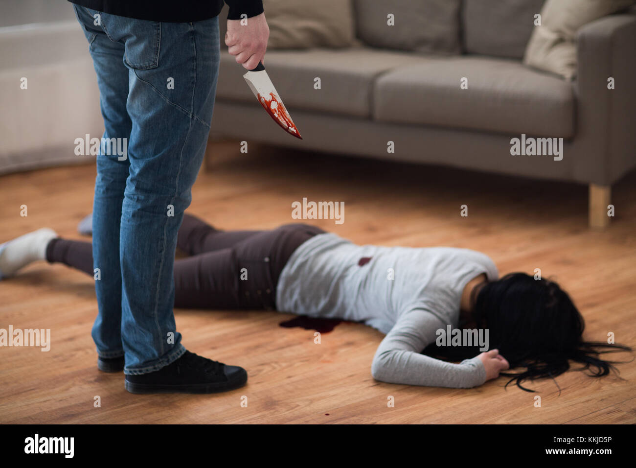 criminal with knife and dead body at crime scene Stock Photo