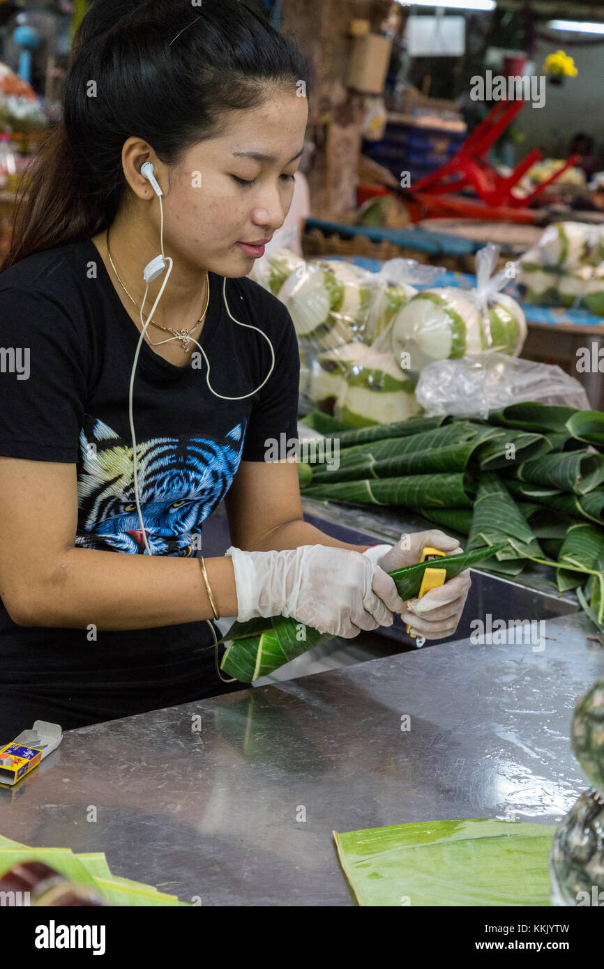 Bangkok, Thailand.  Pak Khlong Market (Flower Market).  Young Woman Making Cones out of Banana Leaves to Hold Flower Bouquets. Stock Photo