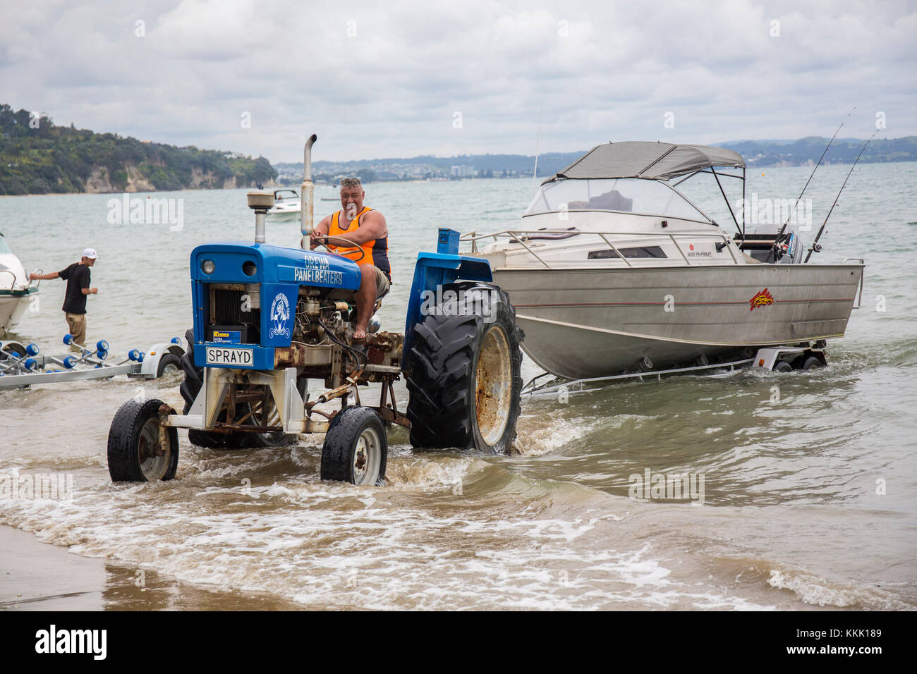 The Stanmore Bay boat club tractor moves a fishermans boat from the bay  Whangaparaoa peninsular Auckland New Zealand Stock Photo