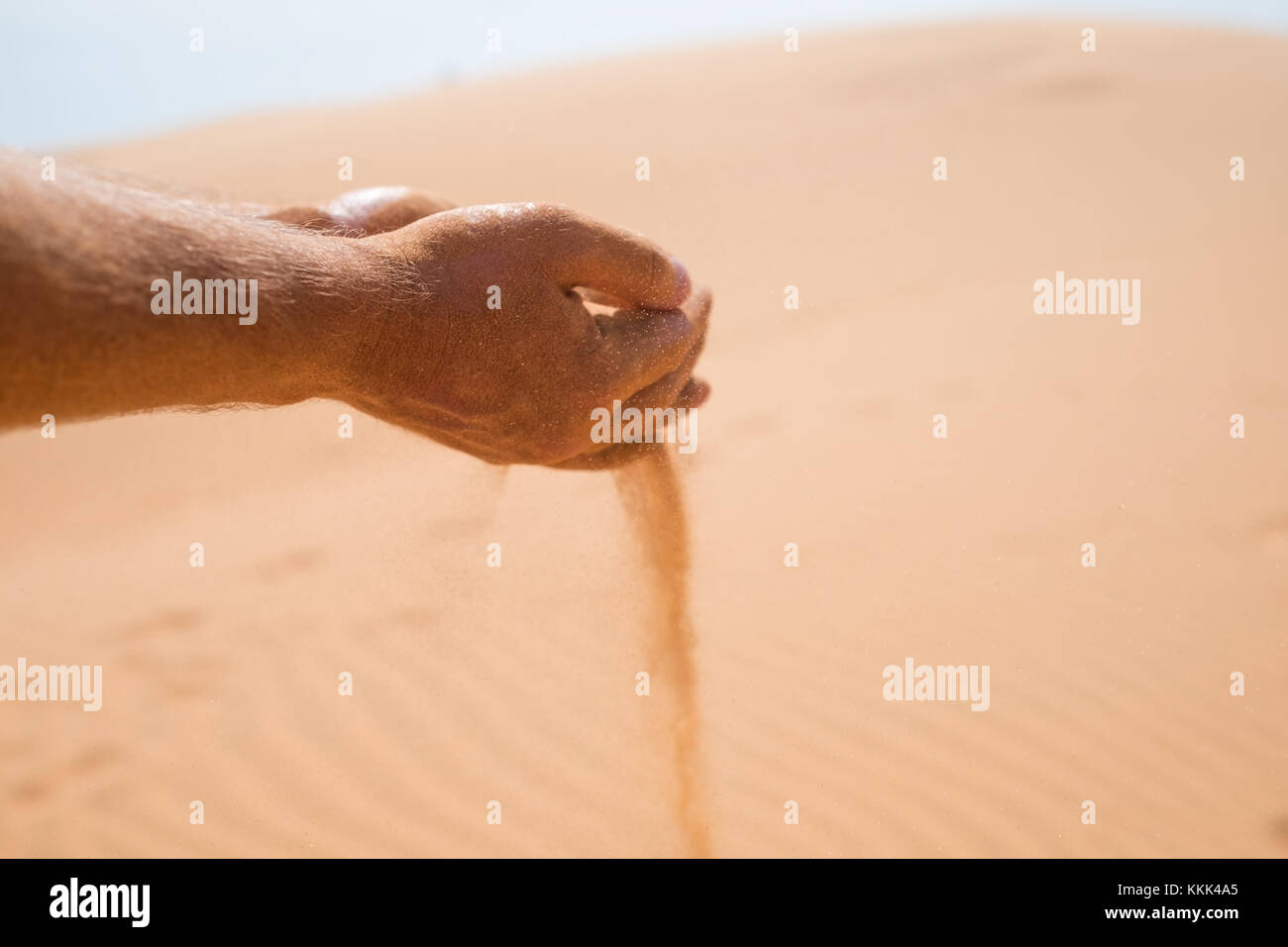 hands with falling sand in desert. Stock Photo
