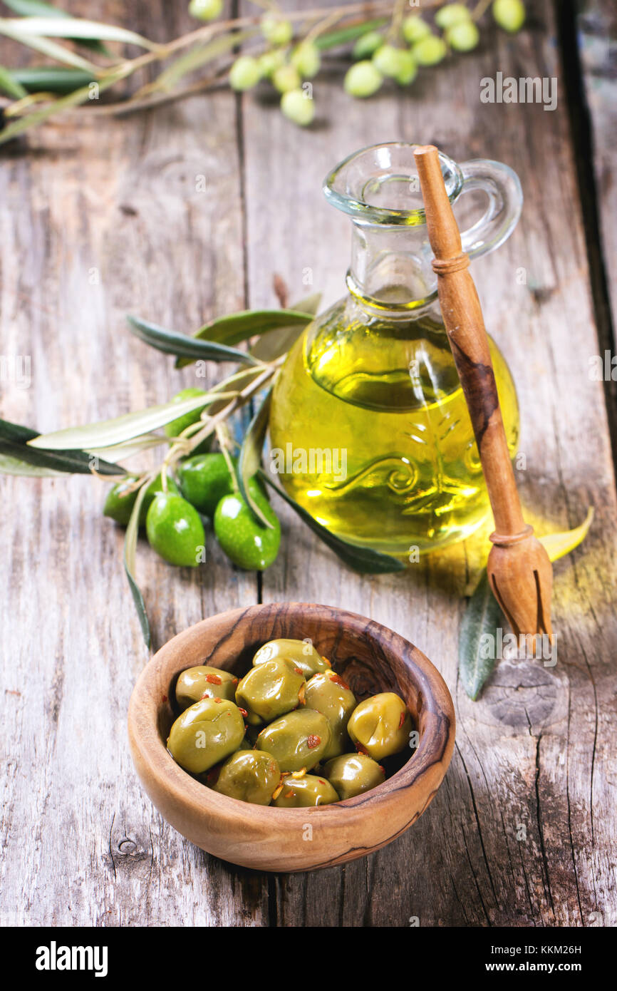 Green olives in olive wood bowl and bottle of olive oil served on old ...