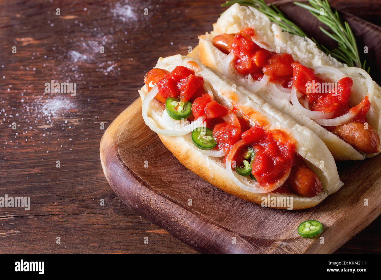 Homemade hot dogs on wooden plate with tomato sauce onion pepper and rosemary on wooden table. With copy space on left Stock Photo Alamy