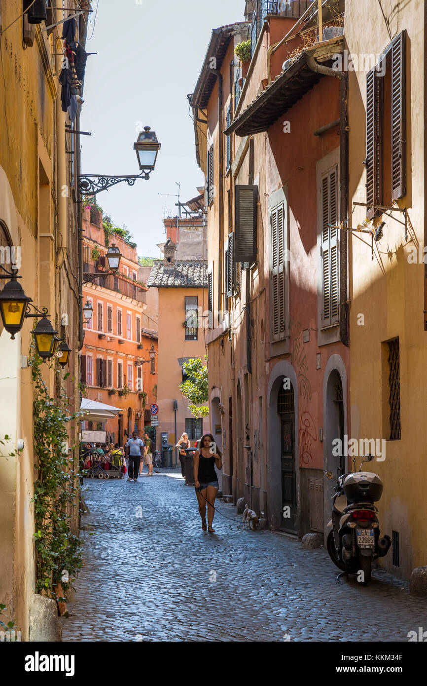 Looking down Via della Pelliccia in the Trastevere area of Rome, Italy with  people sat eating outside a restaurant Stock Photo - Alamy