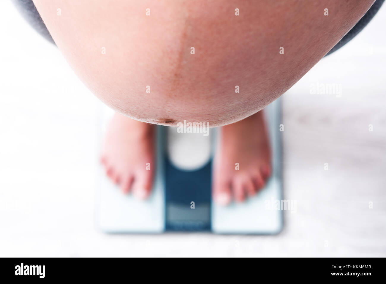 A woman standing on a weighing scale in white background with a lose weight  now note on its display Stock Photo - Alamy