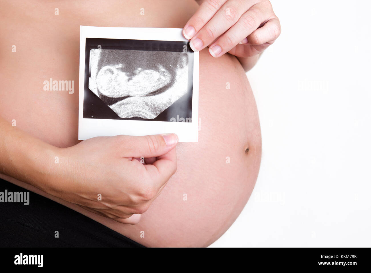 Pregnant woman holding ultrasound scan isolated on white background Stock Photo