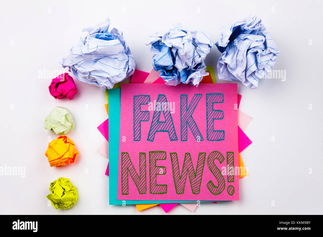 Writing text showing Fake News written on sticky note in office with screw paper balls. Business