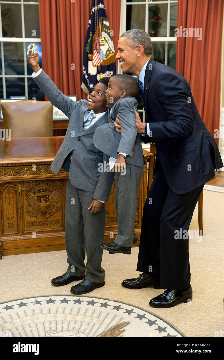 Dec. 4, 2015 'The President acquiesced to a selfie with 11-year-old Jacob Haynes and four-year-old James Haynes after taking a family photograph with departing White House staffer Heather Foster.' (Official White House Photo by Pete Souza) This official White House photograph is being made available only for publication by news organizations and/or for personal use printing by the subject(s) of the photograph. The photograph may not be manipulated in any way and may not be used in commercial or political materials, advertisements, emails, products, promotions that in any way suggests approval  Stock Photo