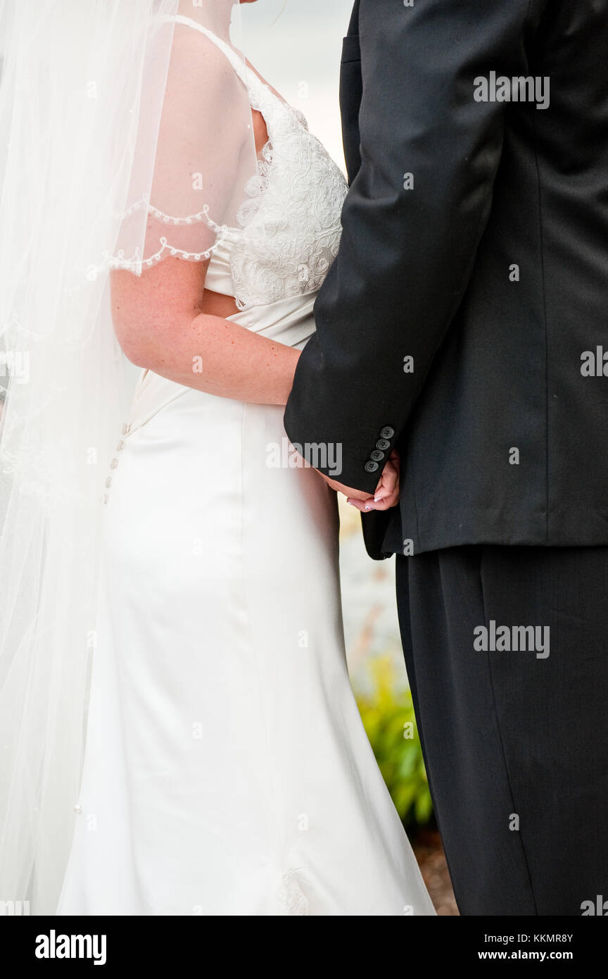 Close up view of bride and groom holding hands during wedding vows